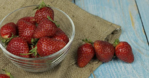 Fresas en una pequeña placa de vidrio sobre una mesa de madera azul — Foto de Stock