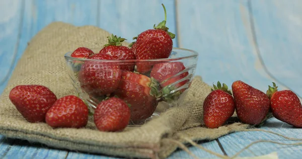 Fresas en una pequeña placa de vidrio sobre una mesa de madera azul — Foto de Stock