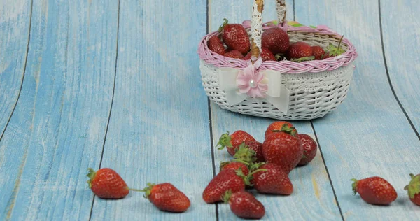 Strawberries in a small basket on the blue wooden background. Place for text — Stock Photo, Image