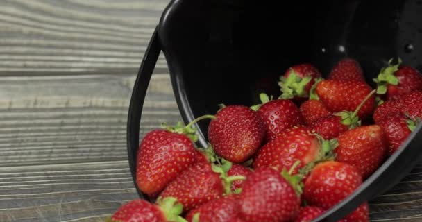 Aardbeien in een kleine zwarte emmer op de houten tafel-close-up — Stockvideo