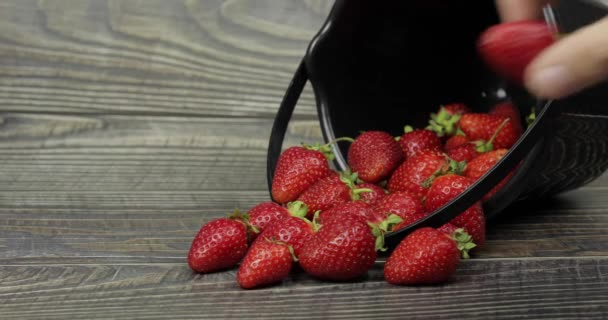 Strawberries in a small black bucket on the wooden table - close up — Stock Video