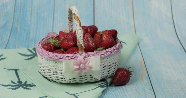 Las fresas en la cesta pequeña sobre la mesa azul de madera - el primer plano — Vídeos de Stock