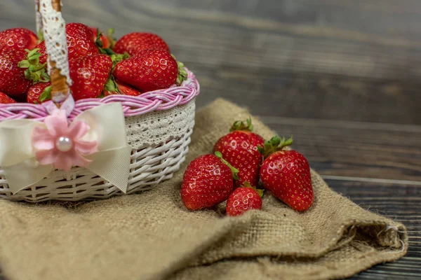 Fresas en una pequeña canasta sobre la mesa de madera. Lugar para su logotipo o texto — Foto de Stock
