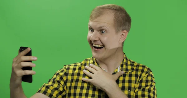 Kaukasische jonge man in geel shirt met behulp van mobiele telefoon voor video-oproep — Stockfoto