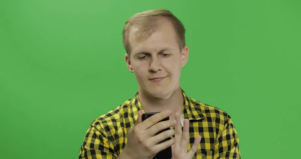 Caucasian fashionable man scrolling or texting on the smartphone in his hands — Stock Photo, Image