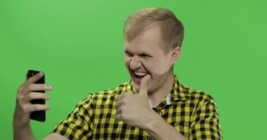 Video araması için cep telefonu kullanarak sarı gömlek Kafkas genç adam