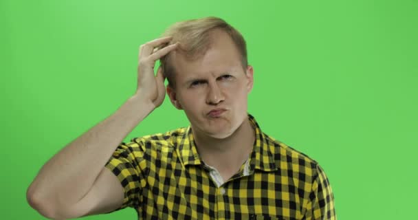 Handsome thoughtful man in yellow shirt looking in the camera and thinks — Stock Video