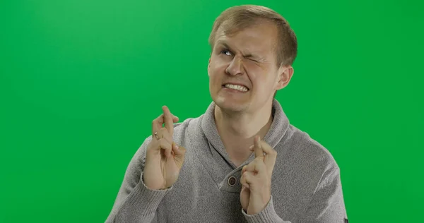 Handsome young man in gray sweater doing lucky gesture. Fingers crossed — Stock Photo, Image