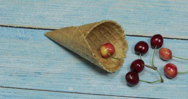 Gelato alle bacche. Bacche di ciliegia in una cialda su uno sfondo di legno blu — Video Stock