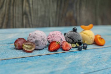 Ahşap bir arka plan üzerinde topları tatlı dondurma. Farklı çilek ve meyveler