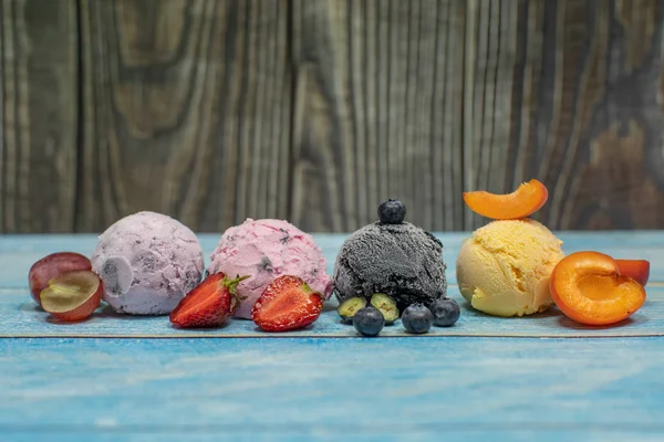 Helado dulce en bolas sobre fondo de madera. Frutos y bayas diferentes — Foto de Stock