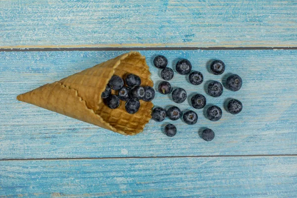 Ягідний морозиво. Ягоди чорниці в вафельних на синьому дерев'яному фоні — стокове фото
