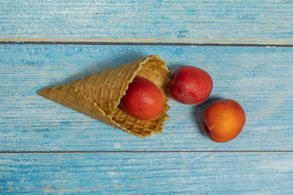 Temporada de frutas. Helado de frutas. Albaricoque en un gofre sobre un fondo de madera azul — Foto de Stock