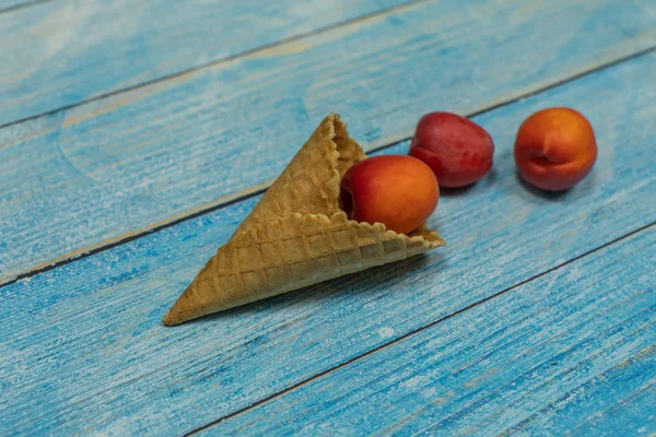 Temporada de frutas. Helado de frutas. Albaricoque en un gofre sobre un fondo de madera azul — Foto de Stock