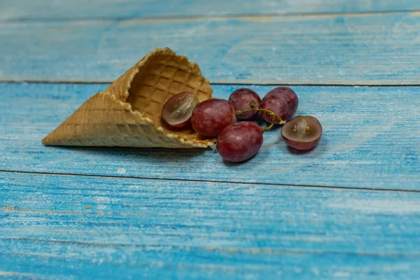 Helado de bayas. Bayas de uva en un gofre sobre un fondo de madera azul — Foto de Stock