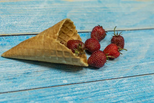 Helado de bayas. Bayas de fresa en un gofre sobre un fondo de madera azul — Foto de Stock