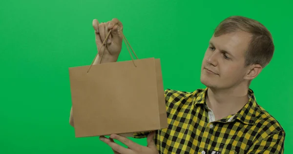 Hombre joven en pantalla verde croma key fondo con bolsa de compras — Foto de Stock