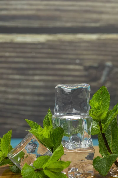 Buz küpleri ve nane yaprakları ahşap kesme tahtası üzerinde izole — Stok fotoğraf