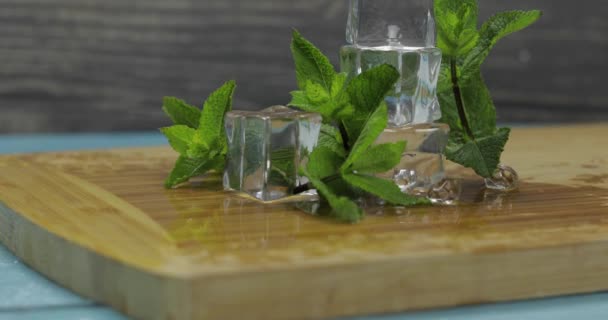 Ice cubes and mint leaves isolated on wooden cutting board — Stock Video