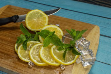 Dilimlenmiş limon, buz küpleri, kesme tahtası üzerinde mojito kokteyl için taze nane yaprakları