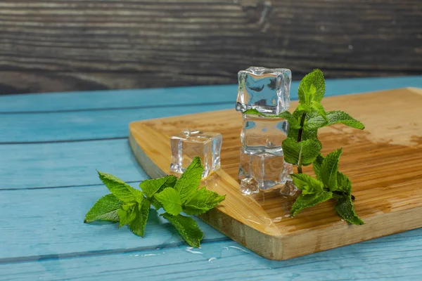 Eiswürfel und Minzblätter isoliert auf einem Holzschneidebrett — Stockfoto