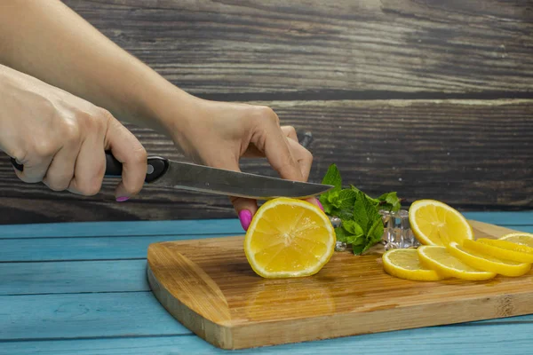 Woman slicing lemon on a wooden cutting board in the kitchen