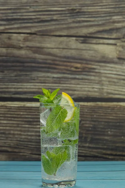 Clear water in glass with green mint leaves and ice cubes