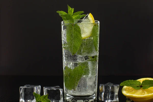 Agua clara en vidrio con hojas de menta verde y cubitos de hielo sobre fondo negro —  Fotos de Stock