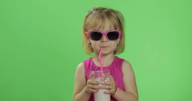 Pembe elbiseli mutlu dört yaşındaki çocuk milkshake kokteyli içer. Renk Anahtarı