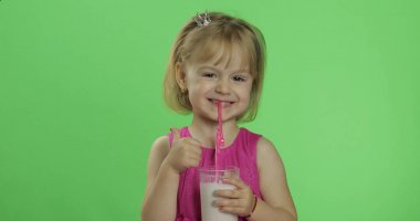 Pembe elbiseli mutlu dört yaşındaki çocuk milkshake kokteyli içer. Çok iyi