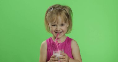 Pembe elbiseli mutlu dört yaşındaki çocuk milkshake kokteyli içer. Renk Anahtarı