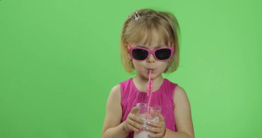 Pembe elbiseli mutlu dört yaşındaki çocuk milkshake kokteyli içer. Renk Anahtarı