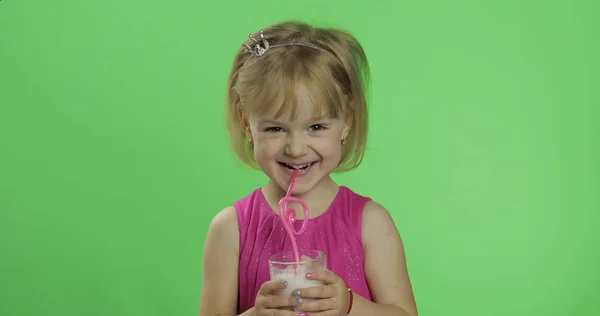 Šťastné čtyři roky staré dítě v růžových šatech pije mléčný koktejl. Klíč Chroma — Stock fotografie