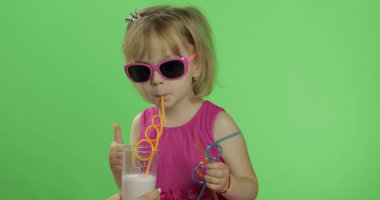 Pembe elbiseli mutlu dört yaşındaki çocuk milkshake kokteyli içer. Çok iyi