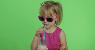 Pembe elbiseli mutlu dört yaşındaki çocuk milkshake kokteyli içer. Renk Anahtarı