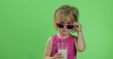 Pembe elbiseli mutlu dört yaşındaki çocuk milkshake kokteyli içer. Renk Anahtarı