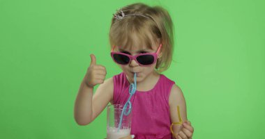 Pembe elbiseli mutlu dört yaşındaki çocuk milkshake kokteyli içer. Çok iyi