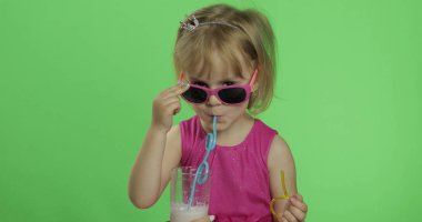 Pembe elbiseli mutlu dört yaşındaki çocuk milkshake kokteyli içer. Renk Anahtarı