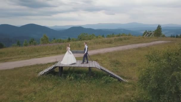 Lugar com a noiva em conjunto em umas colinas de montanha. Drone aéreo disparado — Vídeo de Stock