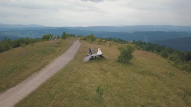 Наречений з нареченою разом на гірських пагорбах. Повітряний безпілотник постріл — стокове відео