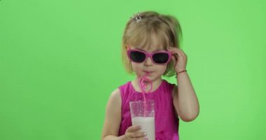 Pembe elbiseli mutlu dört yaşındaki çocuk milkshake kokteyli içer. Renk Anahtarı