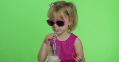 Pembe elbiseli mutlu dört yaşındaki çocuk milkshake kokteyli içer. Renk Anahtarı