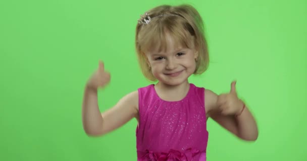 Pembe elbiseli kız başparmaklarını gösterir. Dört yaşında mutlu bir kız. Renk Anahtarı — Stok video