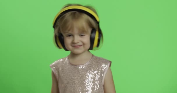 Dziewczynka w błyszczącej sukni i słuchawkach słuchania muzyki i tańca. Klucz chrominancji — Wideo stockowe
