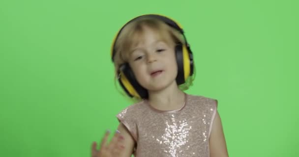 Chica en vestido brillante y auriculares escuchando música y bailando. Clave de croma — Vídeos de Stock