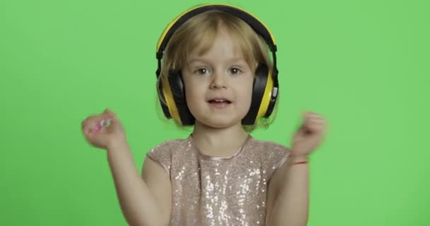 Chica en vestido brillante y auriculares escuchando música y bailando. Clave de croma — Vídeos de Stock