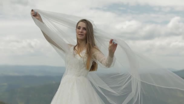 Vacker brud i bröllopsklänning och slöja på bergen. Slow motion — Stockvideo