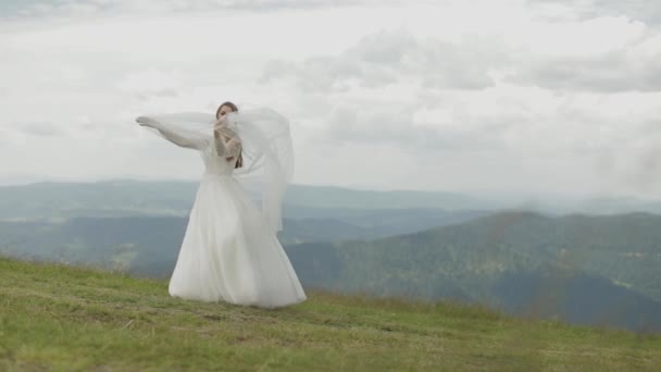 Красива наречена у весільній сукні та завісі на горах. Повільний рух — стокове відео