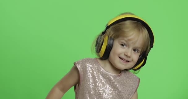光沢のあるドレスとヘッドフォンの女の子は、音楽やダンスを聴いています。クロマキー — ストック動画