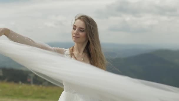 Beautiful bride in wedding dress and veil on the mountains. Slow motion — Stock Video